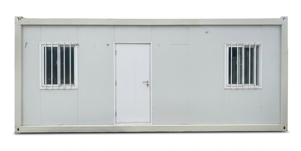 A modular detachable container house being assembled on-site with galvanized steel columns, roof beams, and white sandwich wall panels.